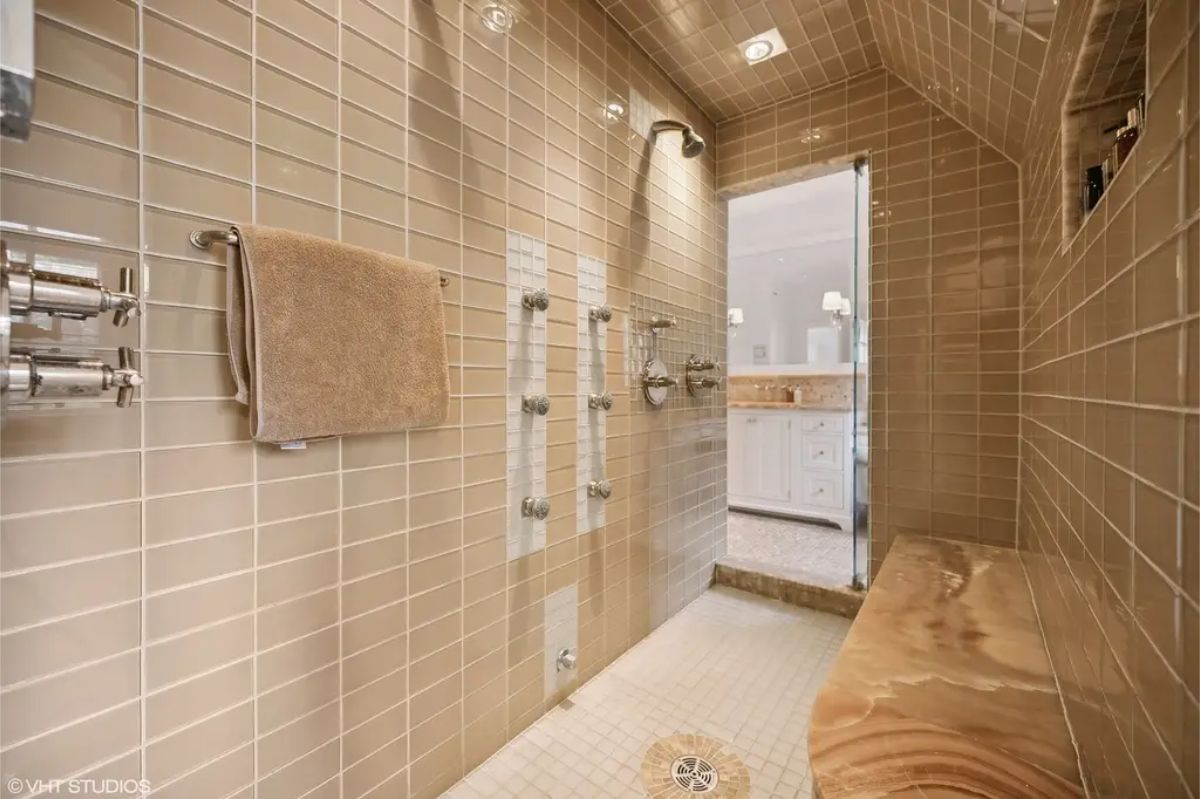 Floor-to-ceiling beige tiles create a cohesive and warm environment in the shower area.