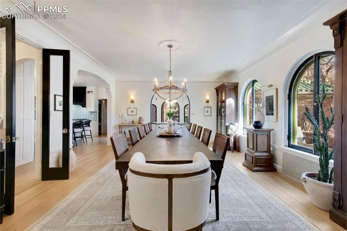 A long table with seating for large gatherings, illuminated by a central chandelier. 