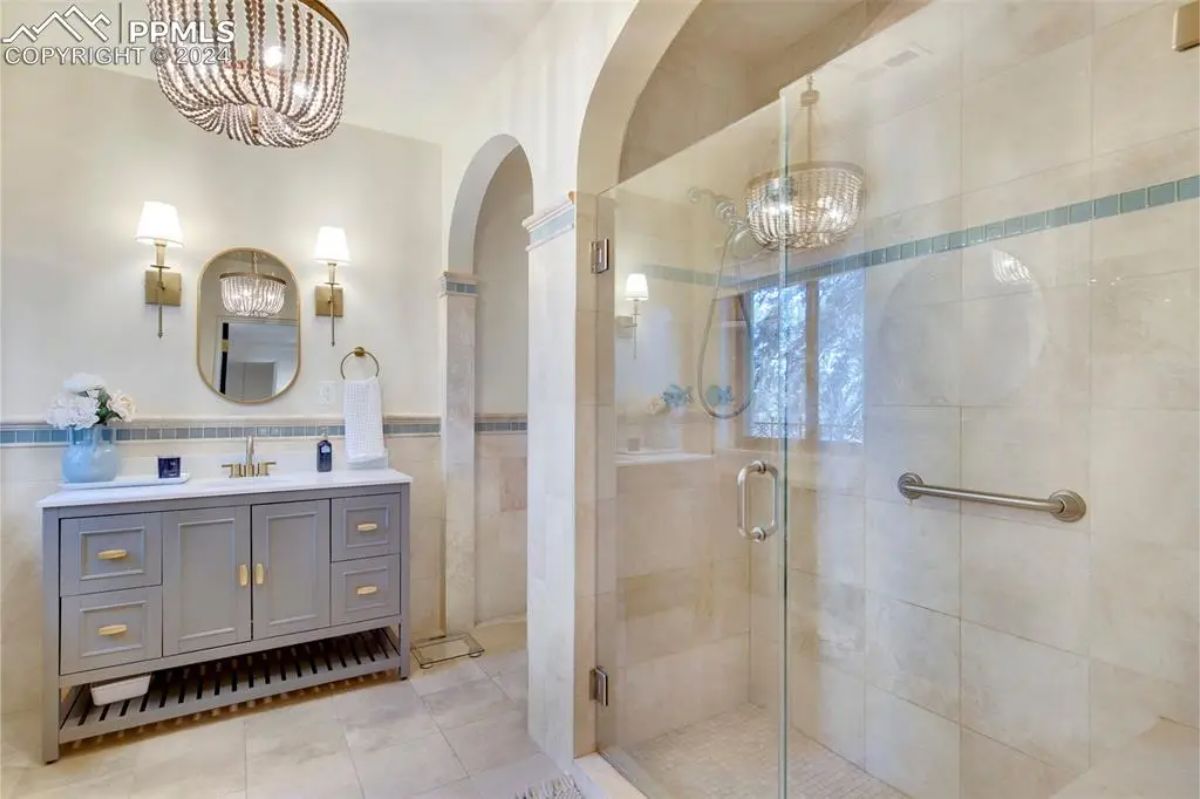 Spacious walk-in shower enclosed in glass, accented with subtle blue tile detailing. 