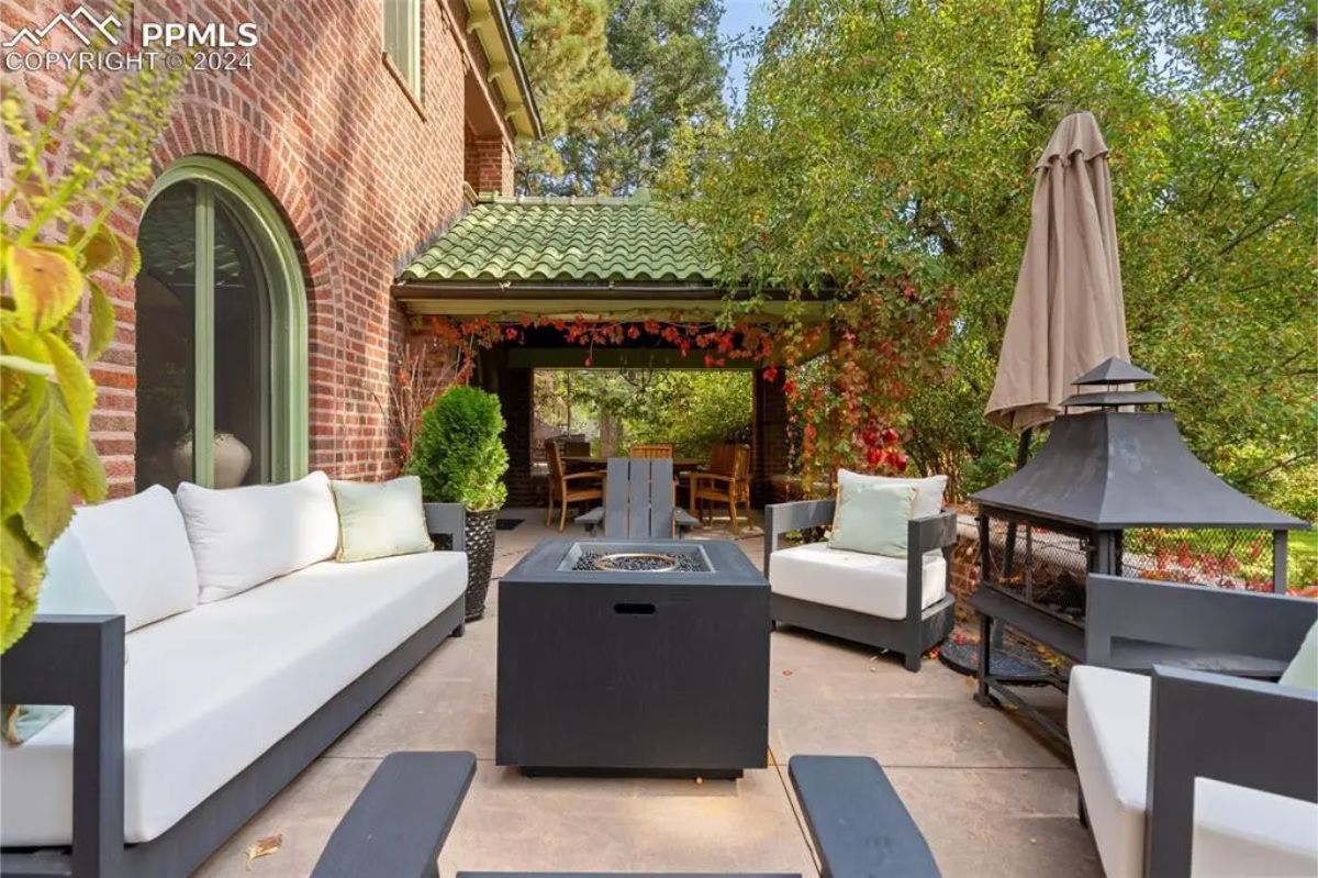 This inviting outdoor patio features a cozy seating arrangement with modern furniture surrounding a sleek fire pit.