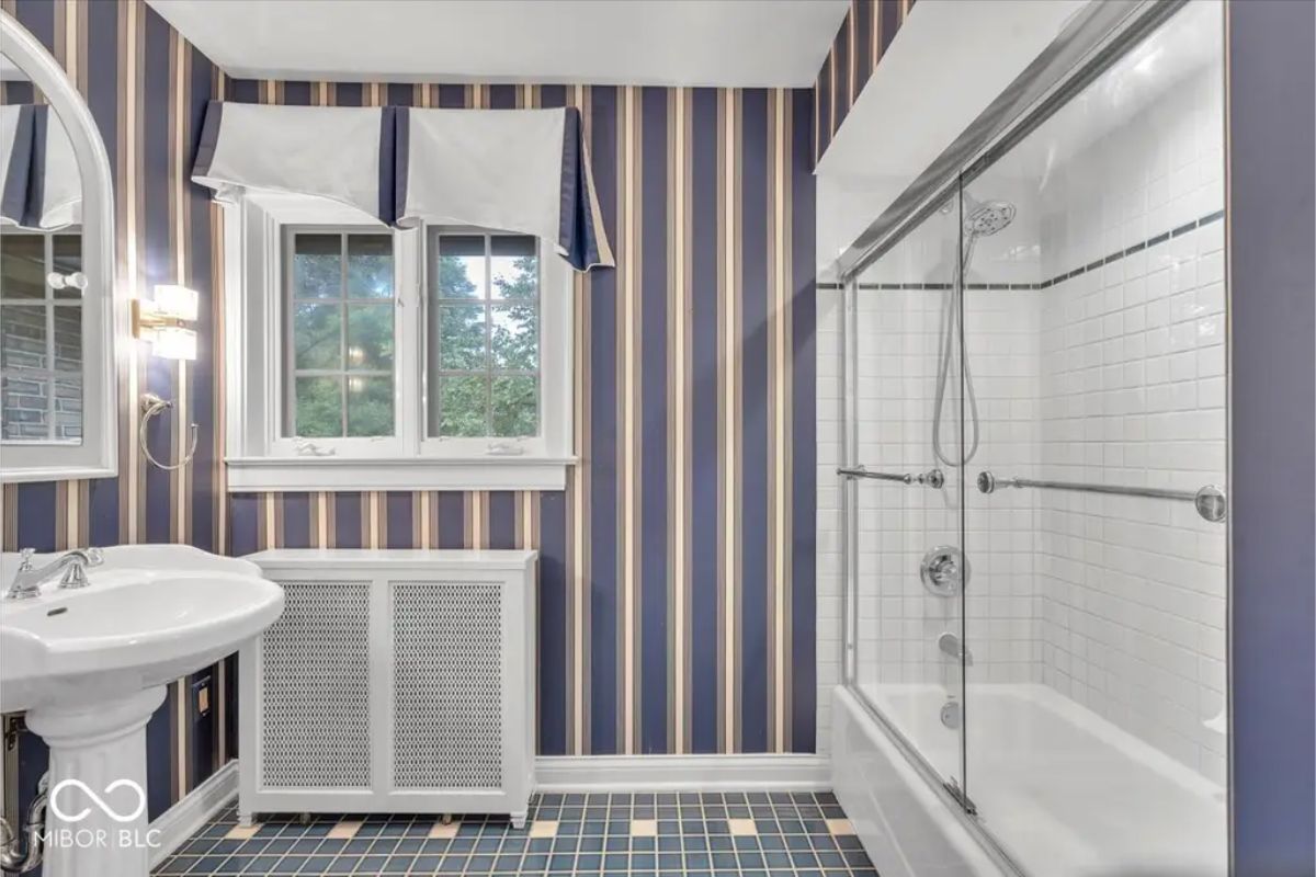 Bold navy and gold striped wallpaper paired with a white pedestal sink.