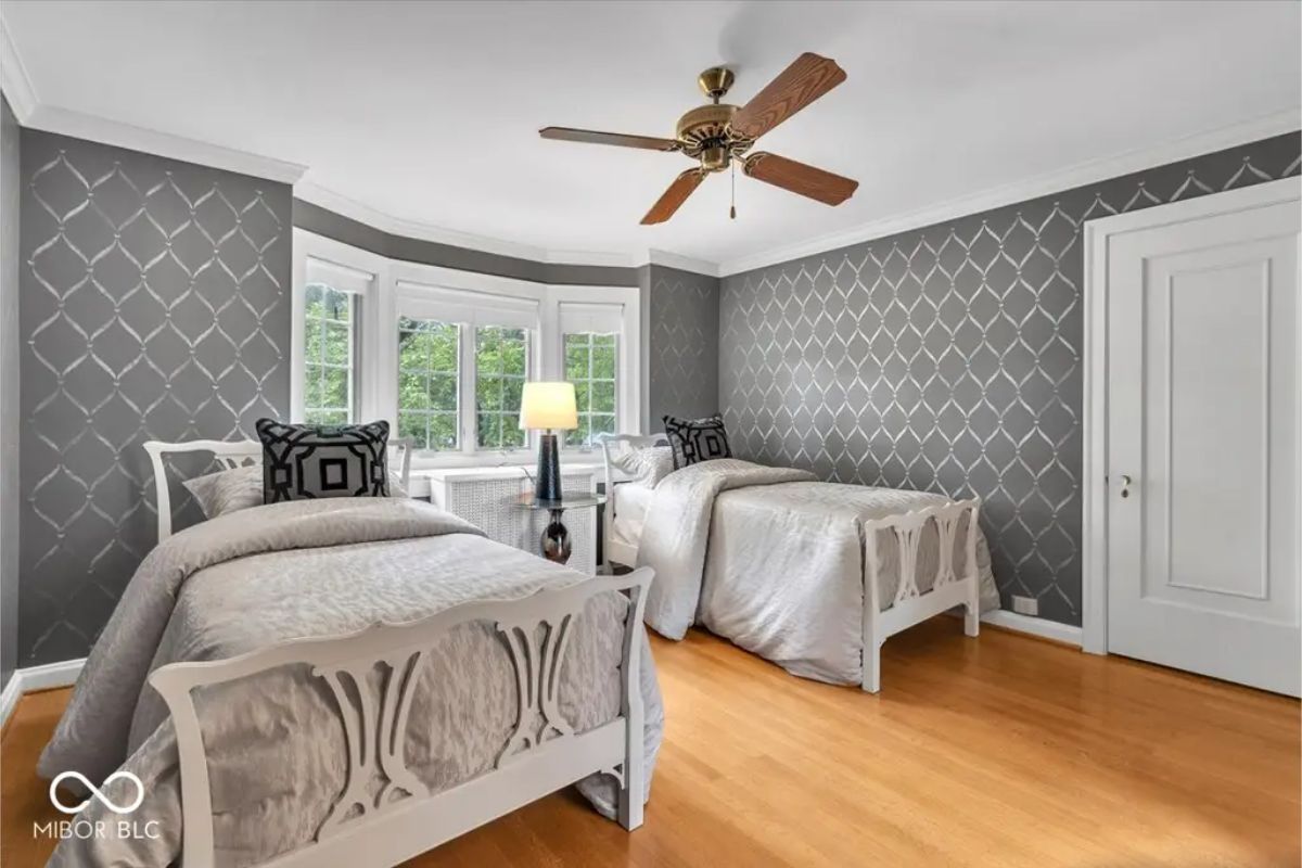 Twin beds with intricately designed headboards and silver-toned bedding.