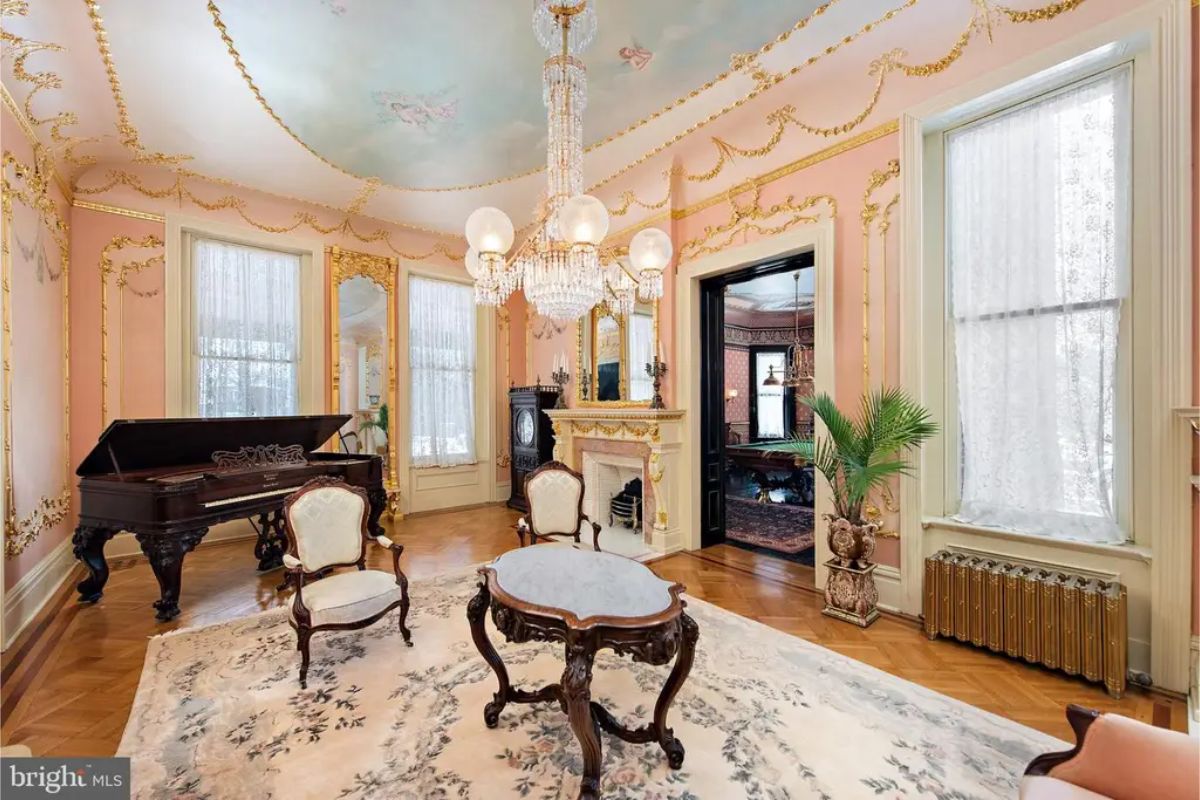 Intricate Victorian craftsmanship with gilded moldings and a large crystal chandelier.