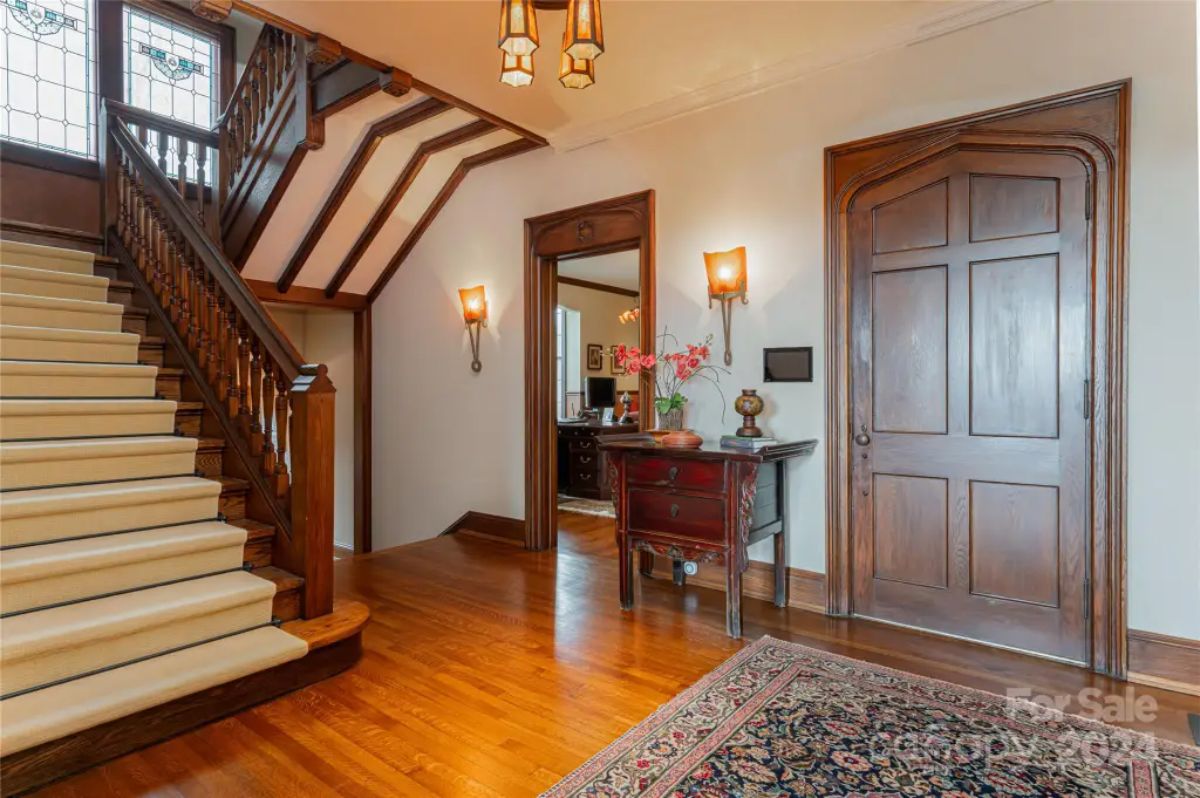 Wood-paneled staircase leads to the upper floor with intricate railing details.