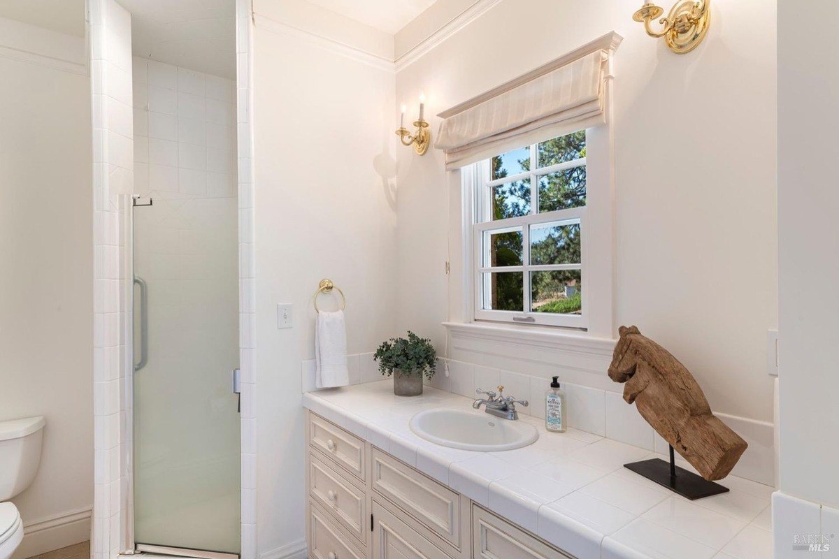 Walk-in shower, a vanity with a marble countertop, and a decorative accent piece, creating a tranquil and luxurious space.