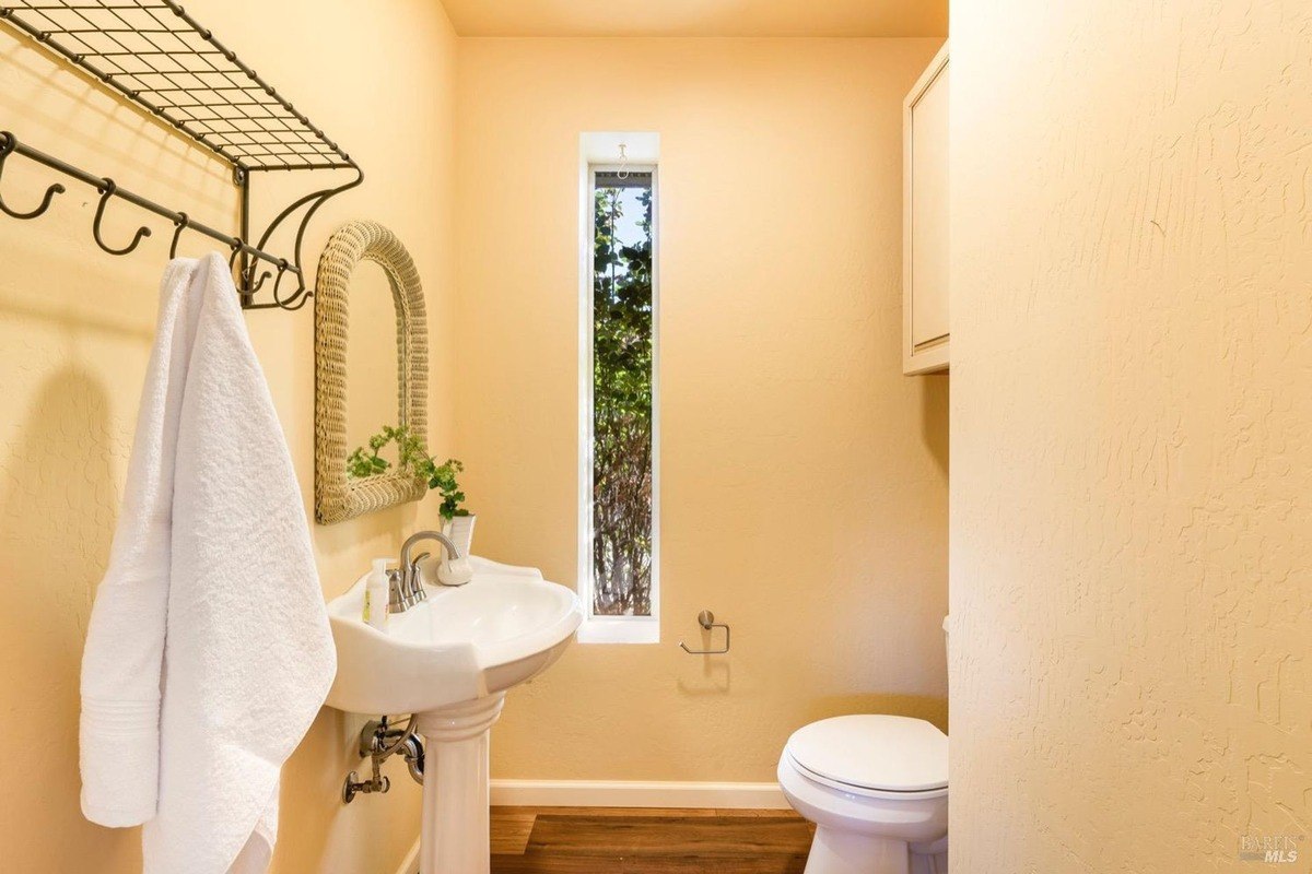 powder room with a pedestal sink, a mirror, and a towel rack.