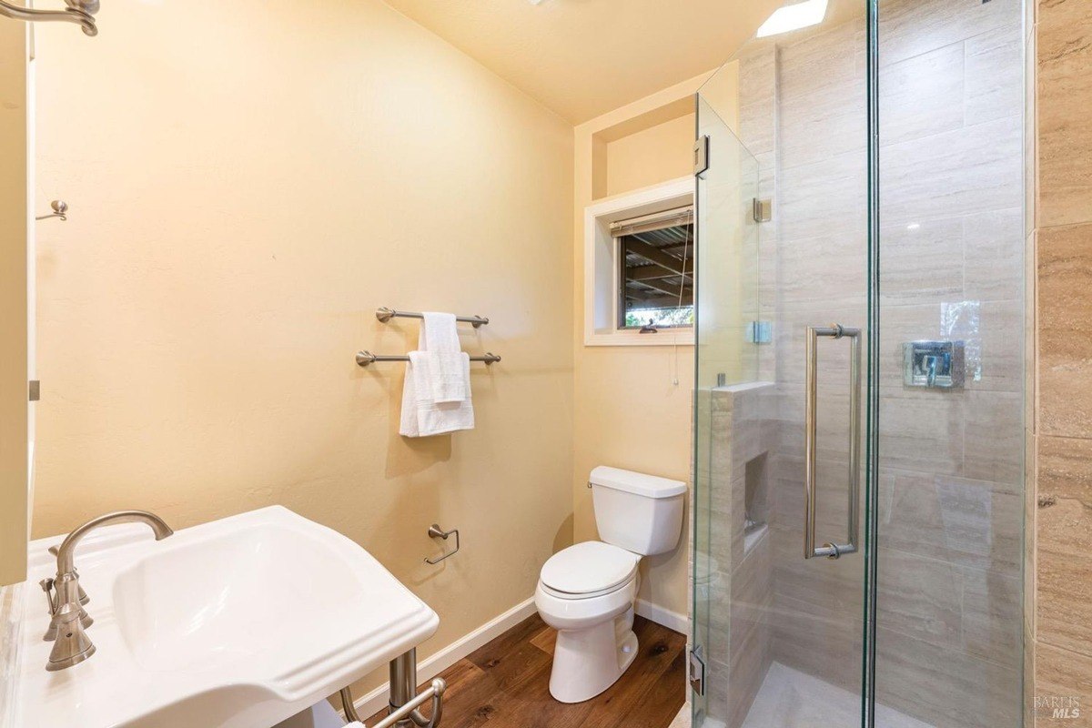 Modern bathroom with a walk-in shower, a pedestal sink, and a toilet.