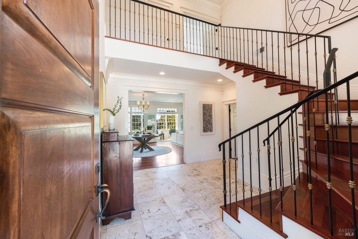 A house with grand entrance with a wooden door and a curved staircase with an ornate railing.