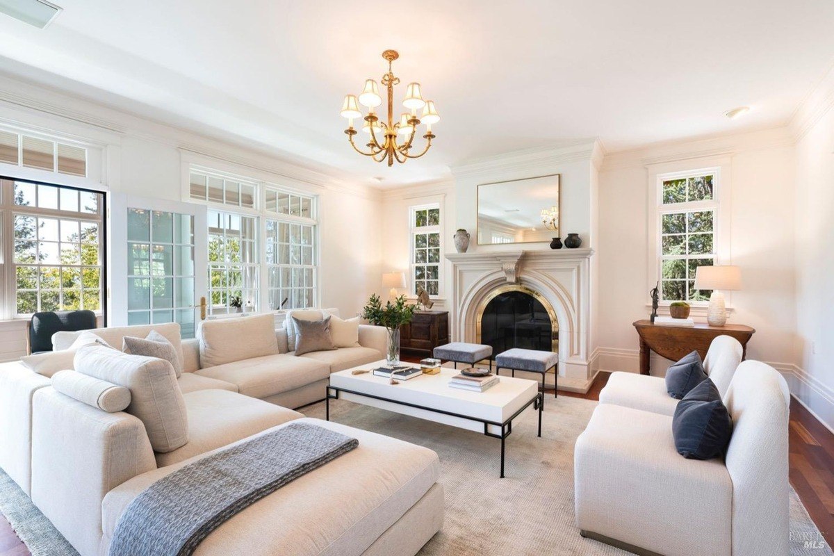 Spacious and elegant living room featuring a plush sectional sofa, a grand fireplace, and a chandelier, creating an inviting atmosphere.