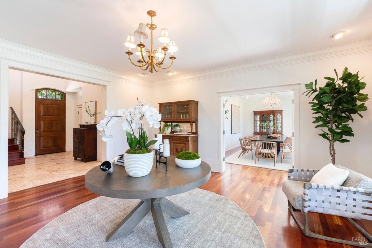 Entryway with hardwood floors, a large round table with flowers, and views of a dining room.