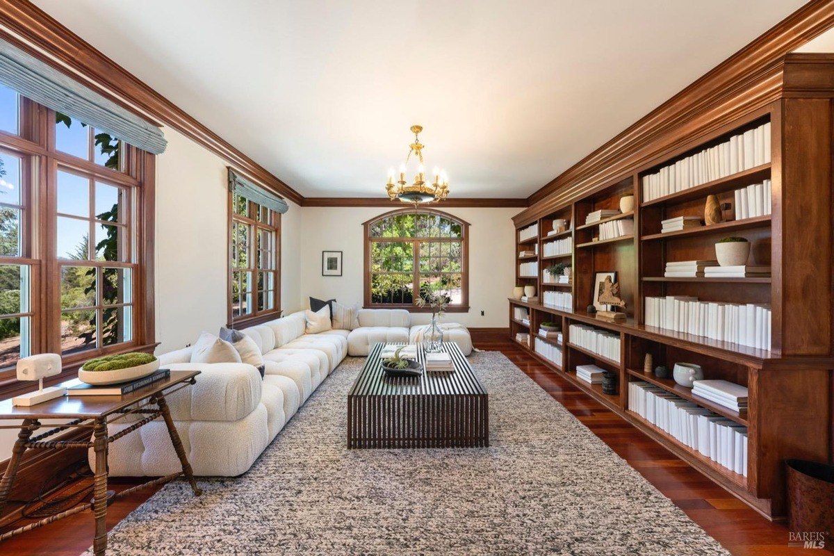 Cozy and inviting reading nook with a plush sectional sofa, a coffee table, and floor-to-ceiling bookshelves, creating a perfect space for relaxation and reading.