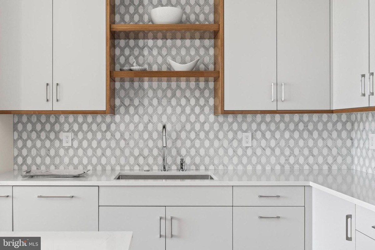 Kitchen features white cabinets, a gray geometric backsplash, and a modern sink.