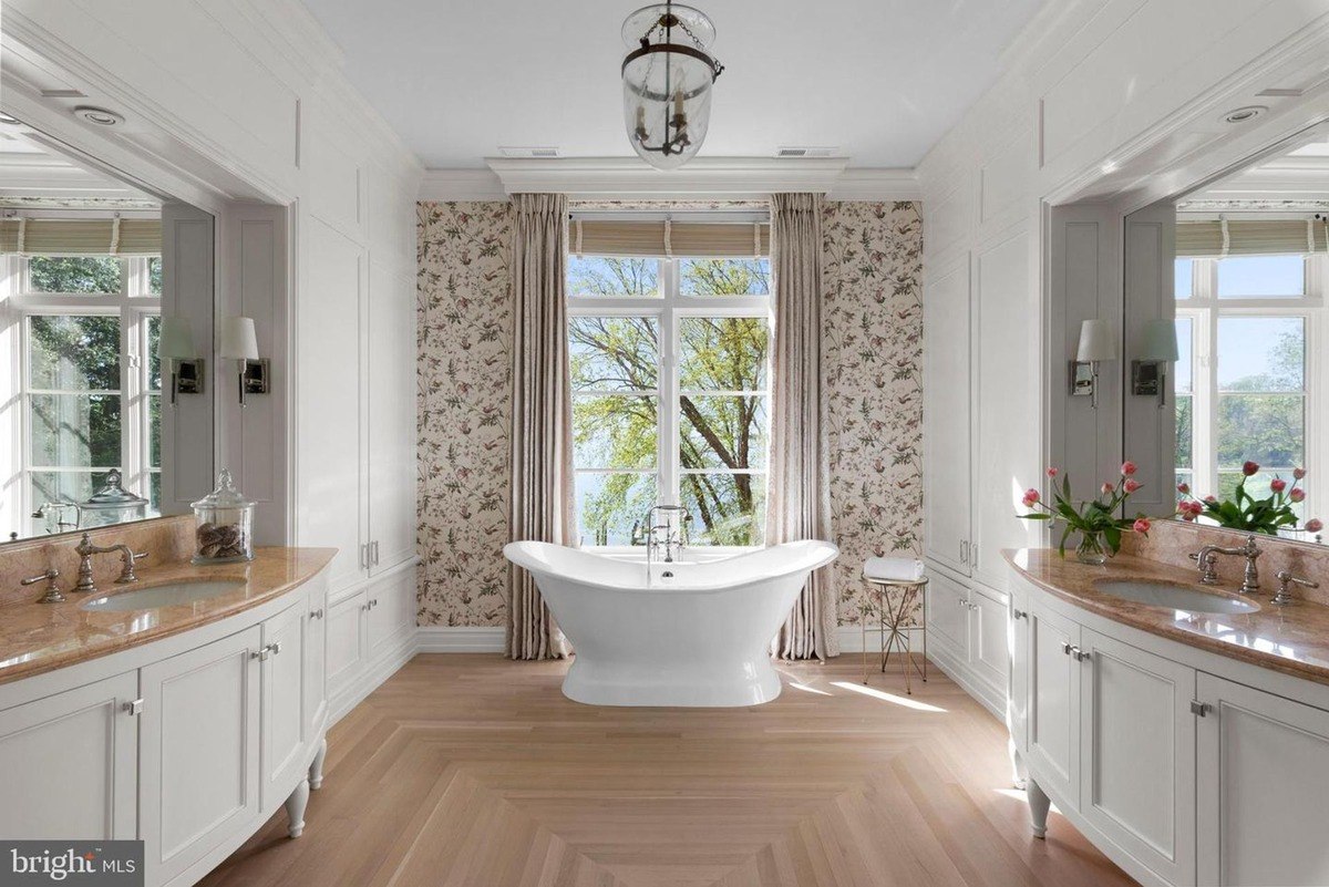 Elegant bathroom features a freestanding bathtub, double vanities, and patterned wallpaper.