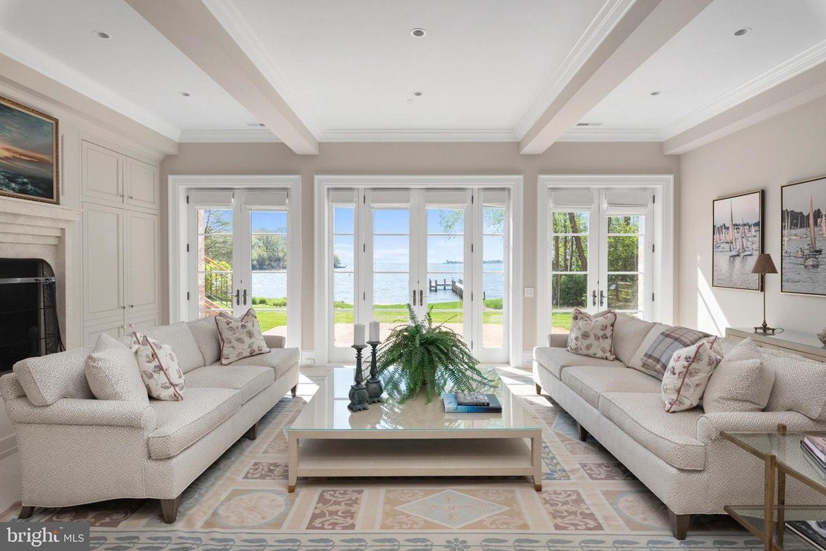 Large living room features two sofas, a coffee table, and expansive windows offering water views.