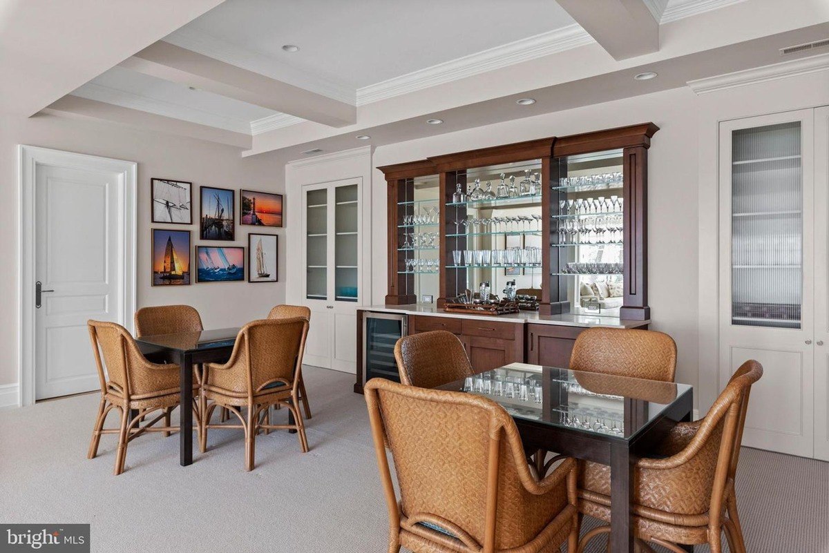 Game room features a wet bar, several wicker chairs, and nautical-themed artwork.