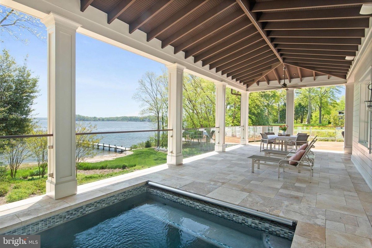 Covered patio offers stunning water views, complete with lounge chairs, a dining set, and a built-in pool.