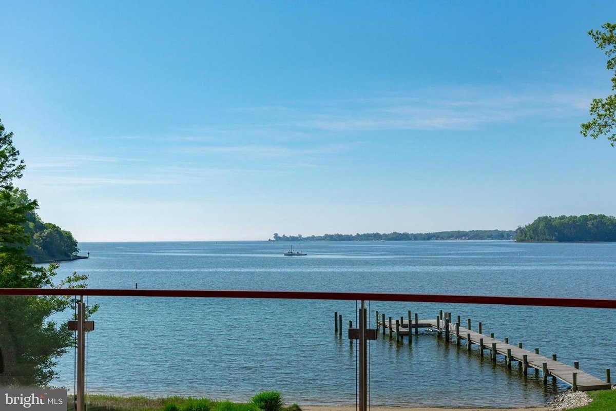 Calm water stretches to a distant shoreline, with a dock and a small boat visible in the foreground.