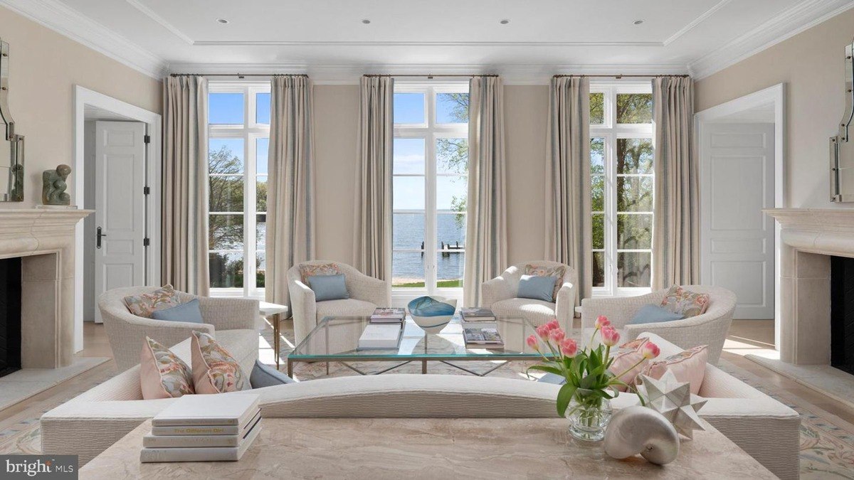 Living room with large windows offering water views, light beige walls, and comfortable seating.