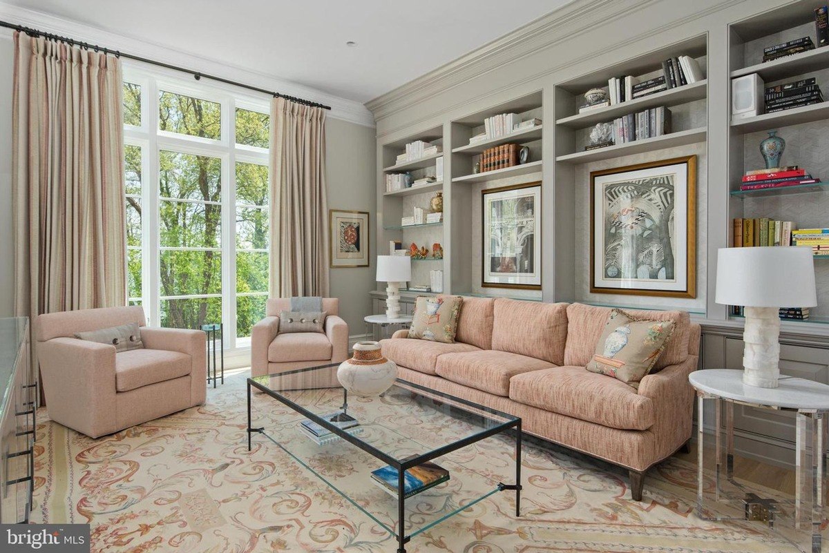 Living room features a blush-toned sofa, built-in bookshelves, and large windows overlooking trees.