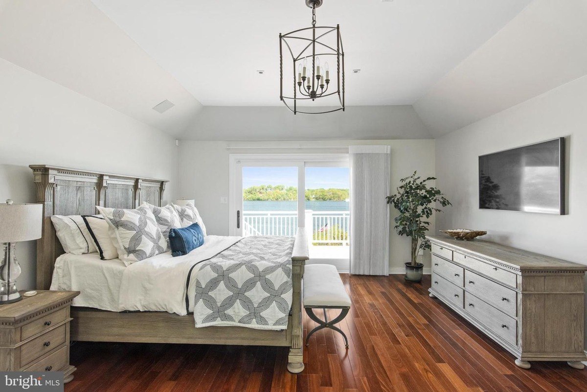 Bedroom has a large bed, dresser, and a view of water.