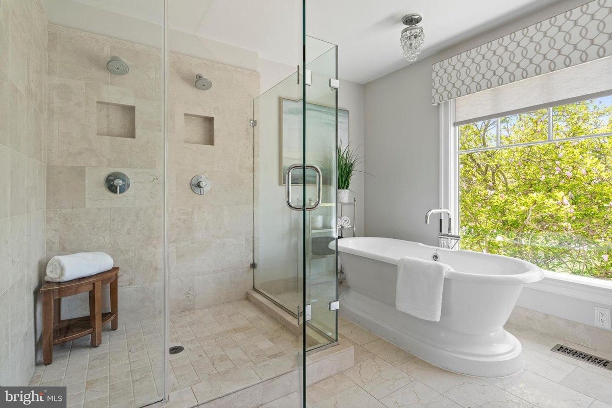 Bathroom has a large soaking tub, walk-in shower, and window with a view of trees.