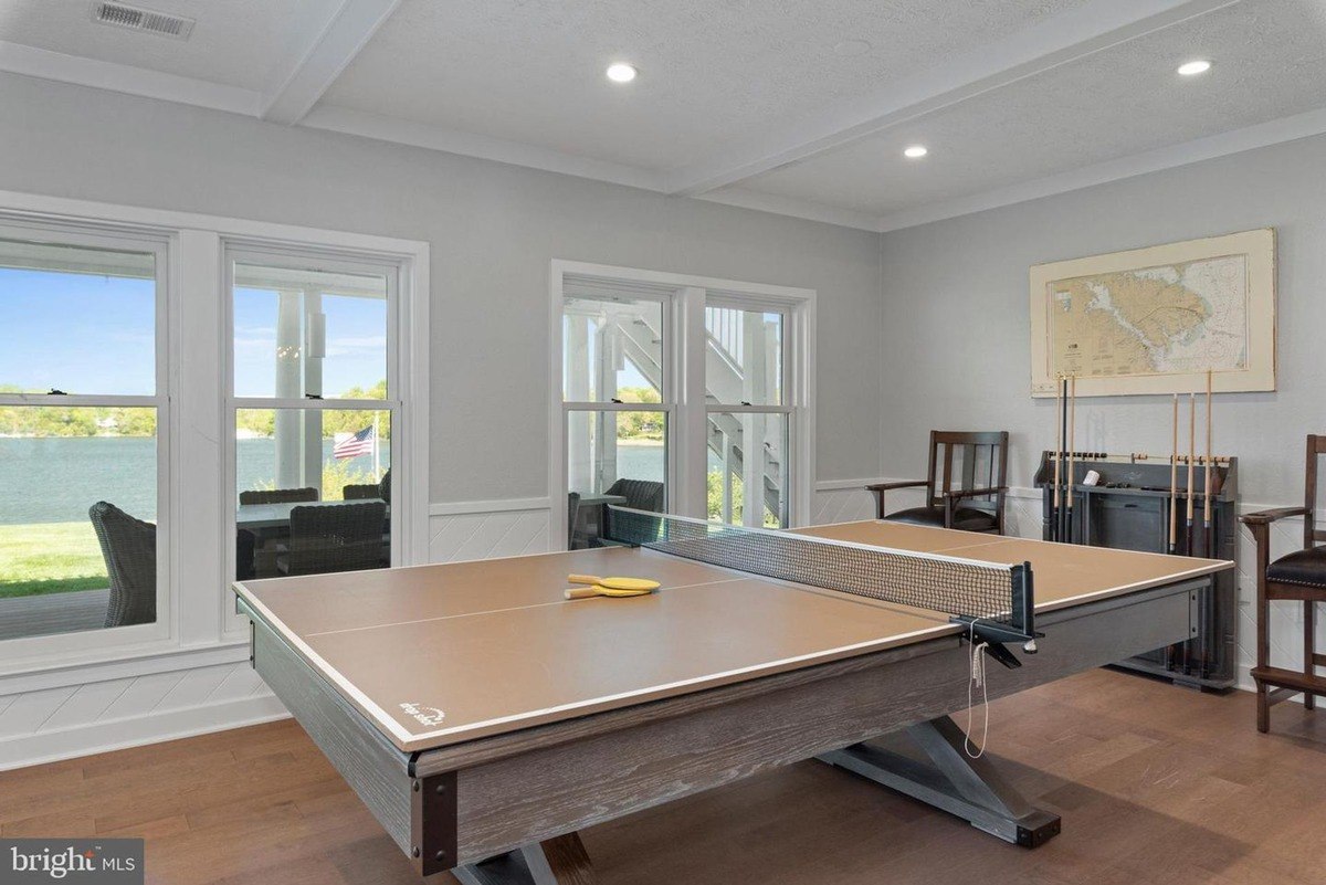 Game room has a ping pong table, hardwood floors, and a view of water.