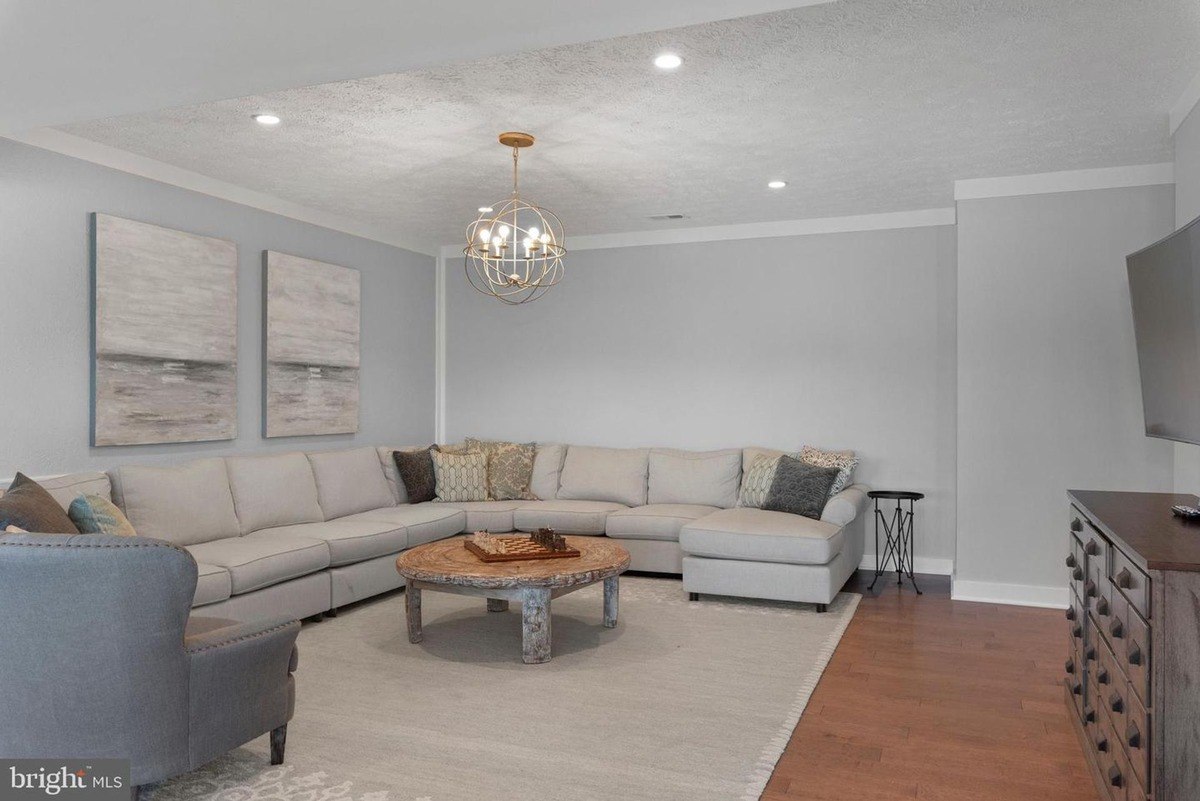 Recreation room has a large sectional sofa, area rug, and hardwood floors.