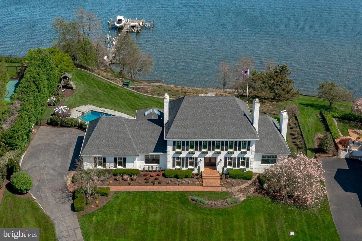 House is white with black shutters, has a pool, and is on a waterfront property.