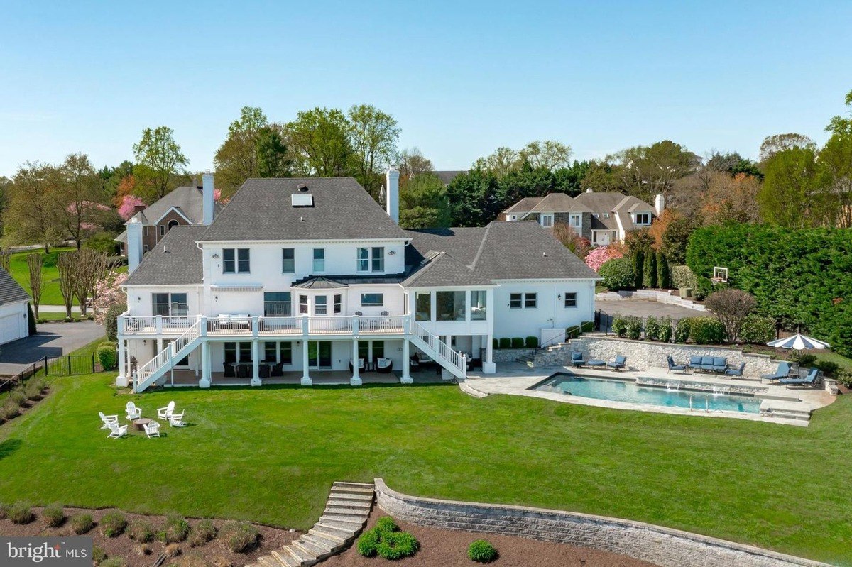 Spacious white house with a pool and adjoining deck.