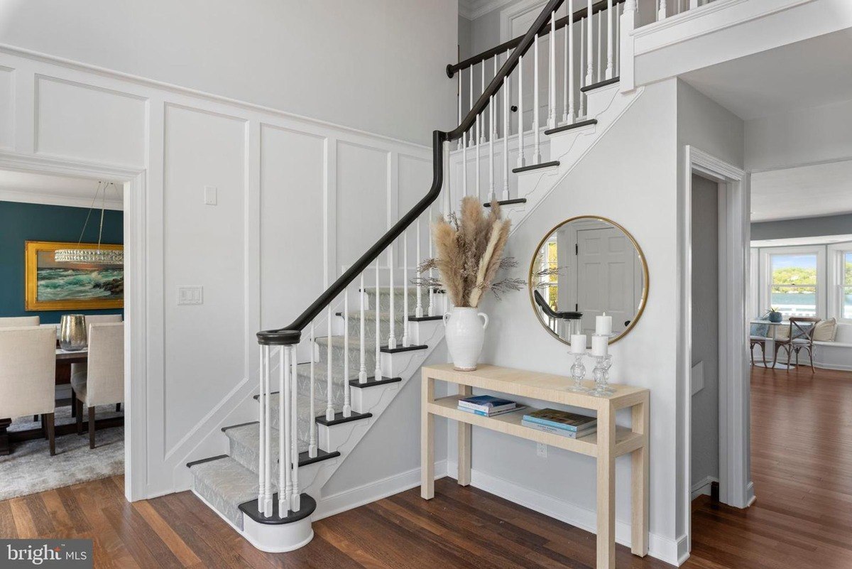 Entryway has a staircase, console table, and view of dining room.