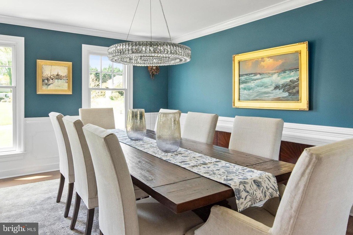 Dining room has a large wood table, blue walls, and a chandelier.