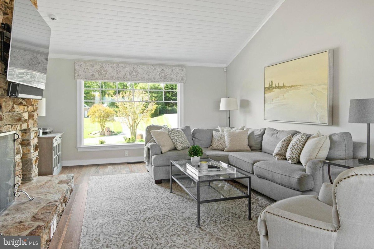 Living room has gray sectional sofa, large window, and area rug.