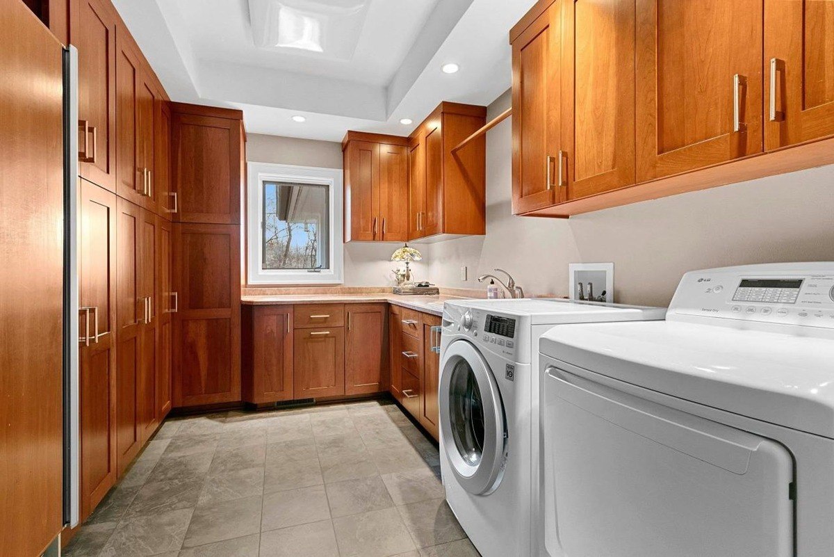 Laundry room with wood cabinets, tile floor, and a washer and dryer.