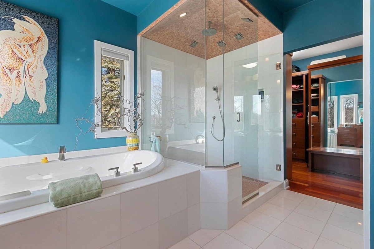 Bathroom with blue walls, white tile, a large tub, and a glass shower.