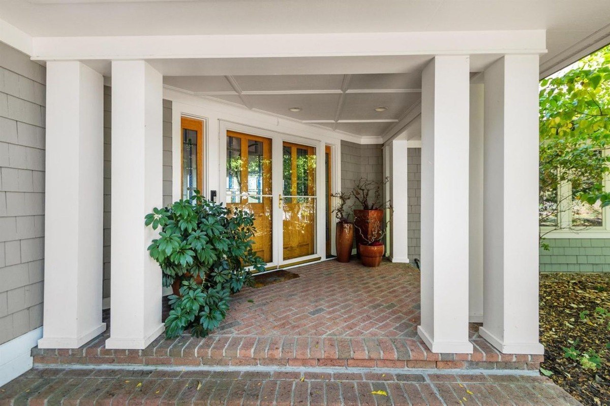 House has brick porch with white columns and double wood doors.