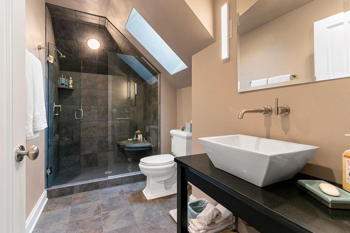 Bathroom has a single sink, a glass shower with stone tile, and a toilet.