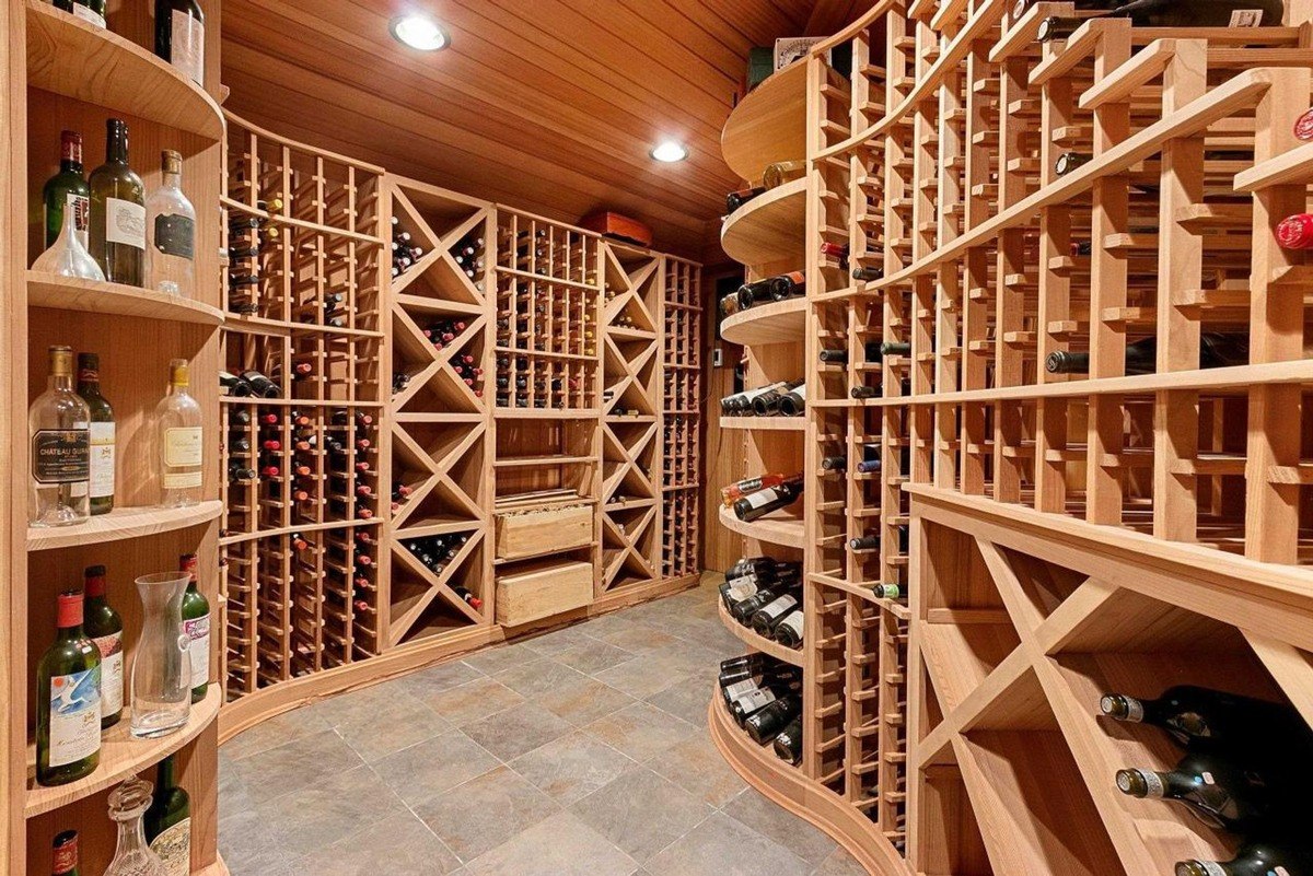 Wine cellar has wood racks, bottles of wine, and tile floor.