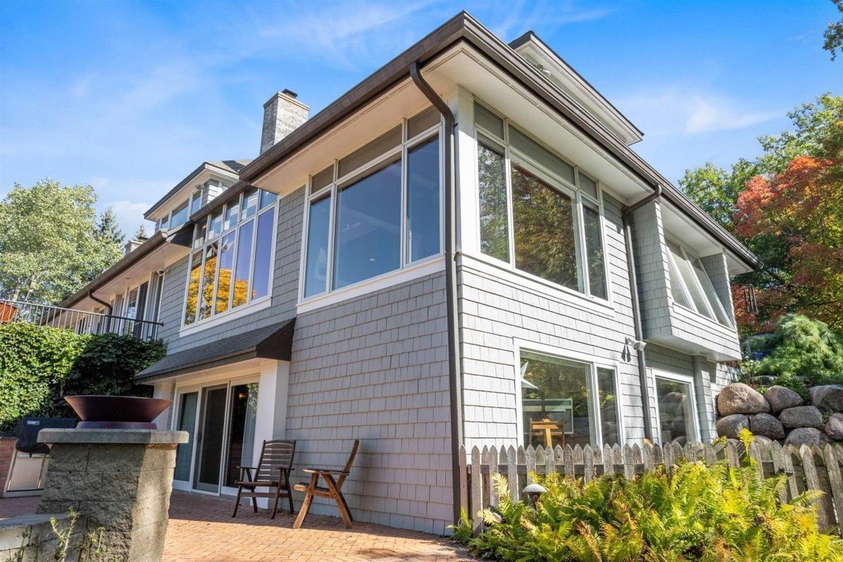 House has gray siding, many windows, and a brick patio.