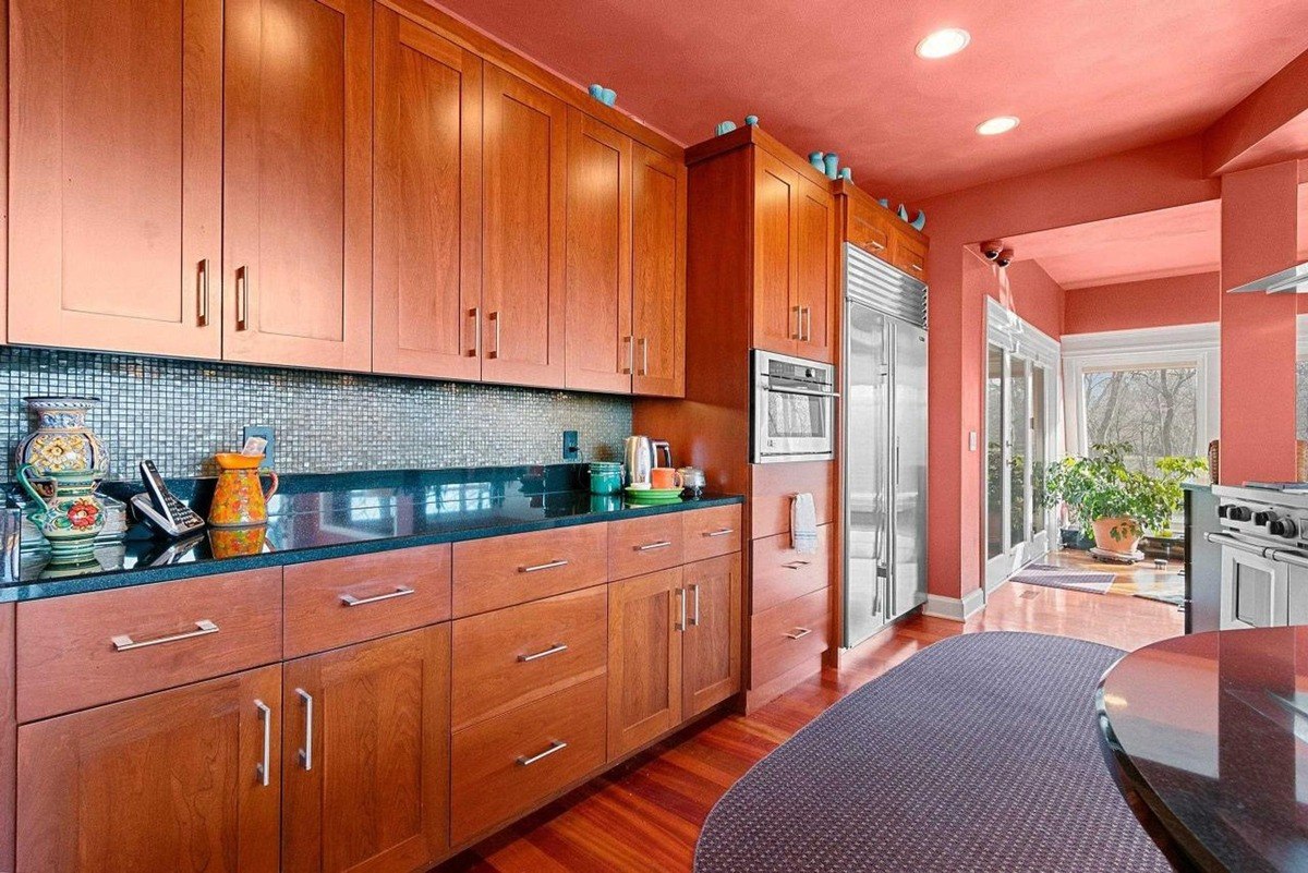 Kitchen with wood cabinets, granite countertops, and orange walls.