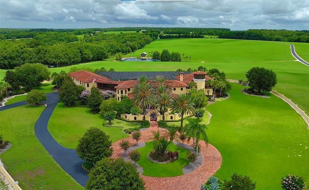 Large estate features a Mediterranean-style mansion surrounded by lush green lawns and landscaping.