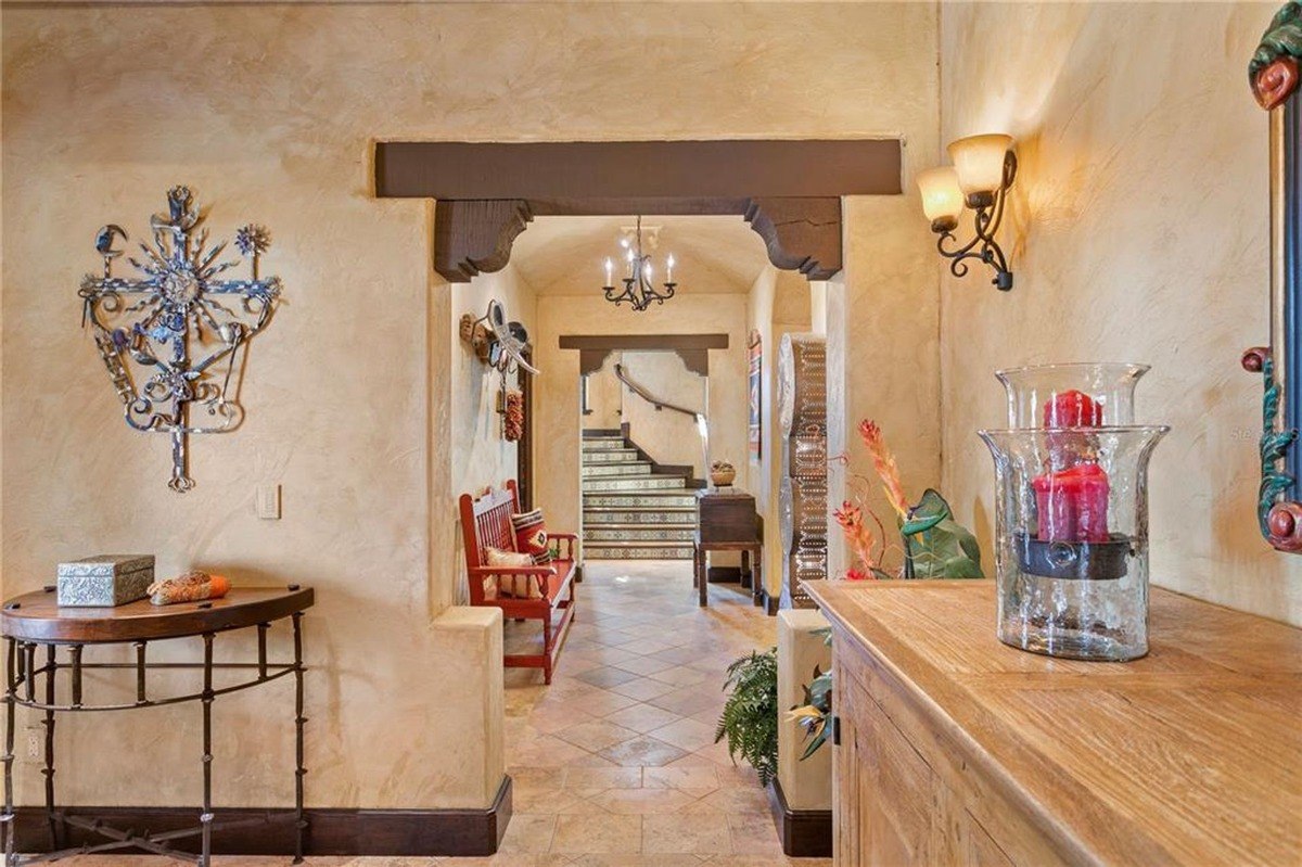 Entryway features a rustic design with decorative wall art, a wooden bench, and a view of a tiled staircase.