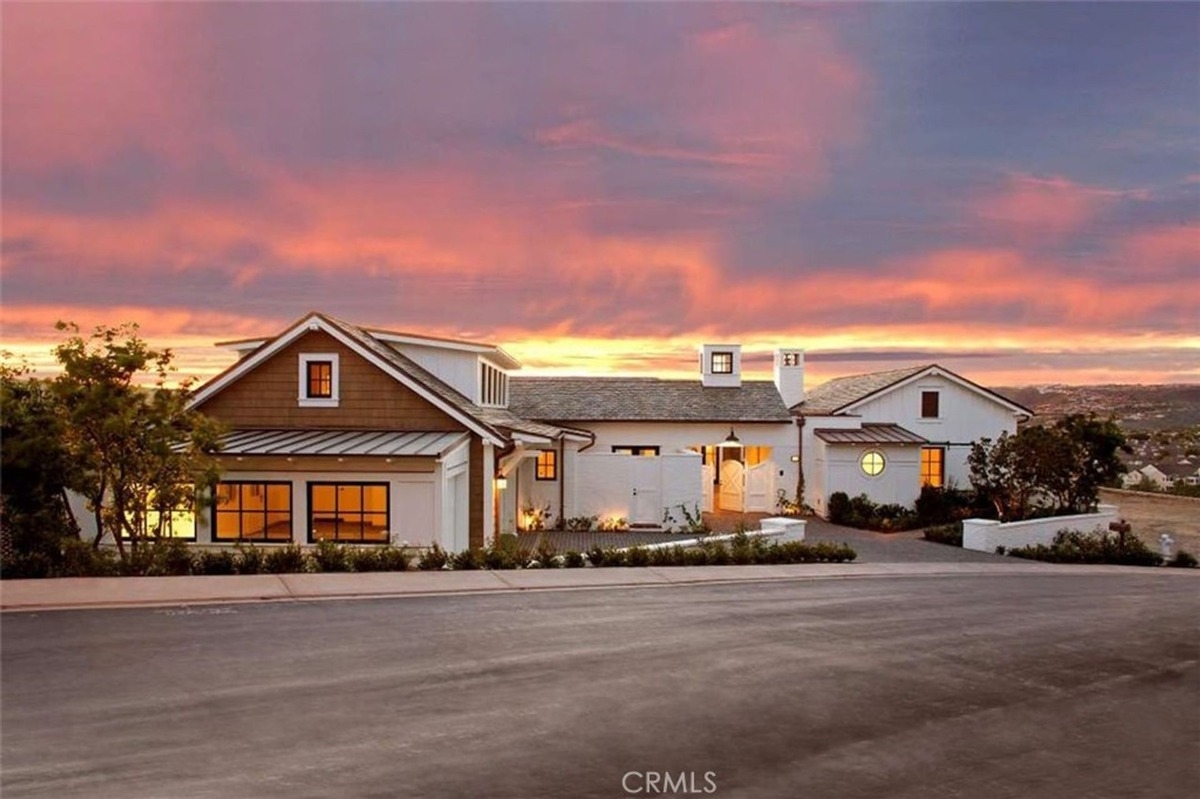 Warm sunset glow illuminates the front facade of a coastal home.