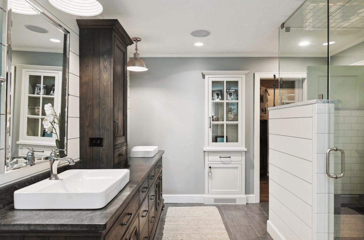 Bathroom vanity view a closer look at the vanity area with a long wooden countertop, white sinks, and glass-door cabinetry.