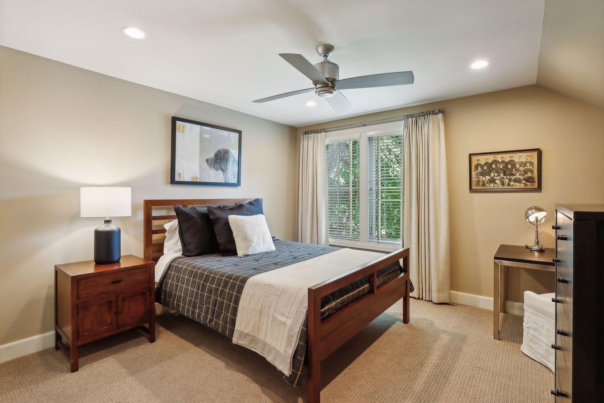 Guest bedroom a bedroom with neutral tones, a ceiling fan, and simple decor centered around a wooden bed frame.