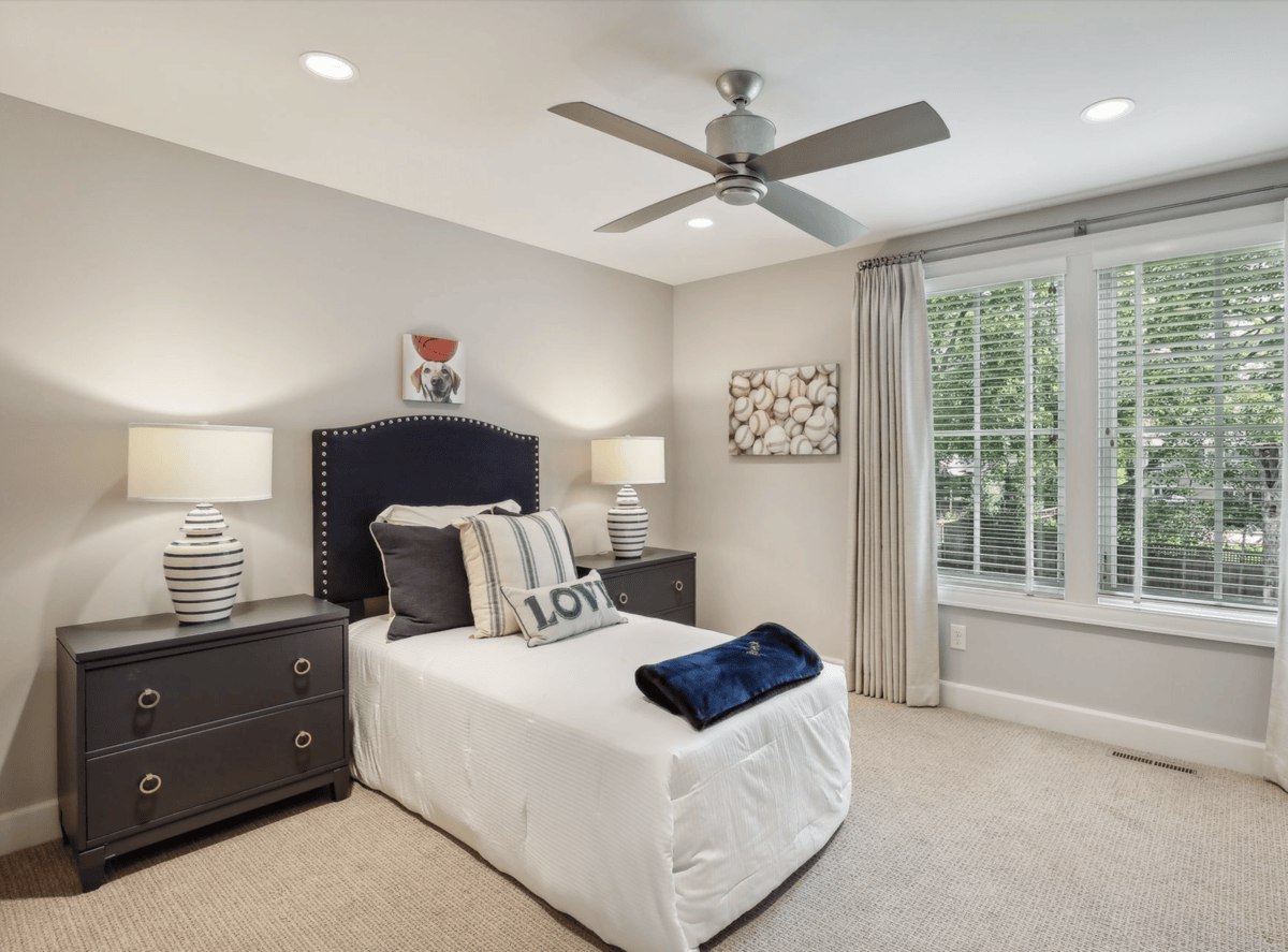 Second guest bedroom a cozy bedroom featuring a navy headboard, nautical accents, and large windows.