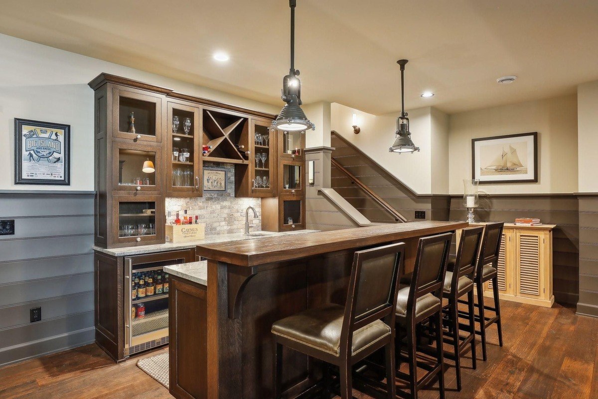 Stylish bar with dark cabinetry, pendant lighting, and high-backed bar stools.