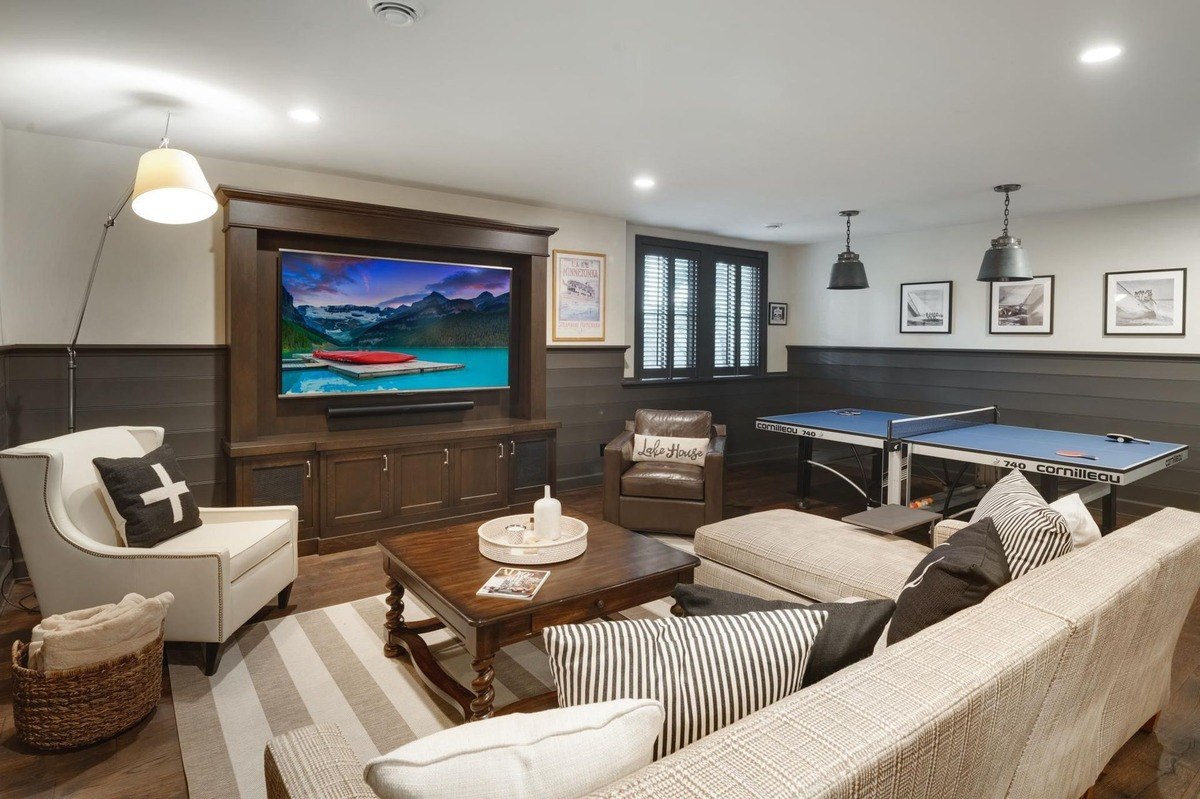 Cozy seating area with plaid-accented chairs, a brown leather sofa, and a mounted TV