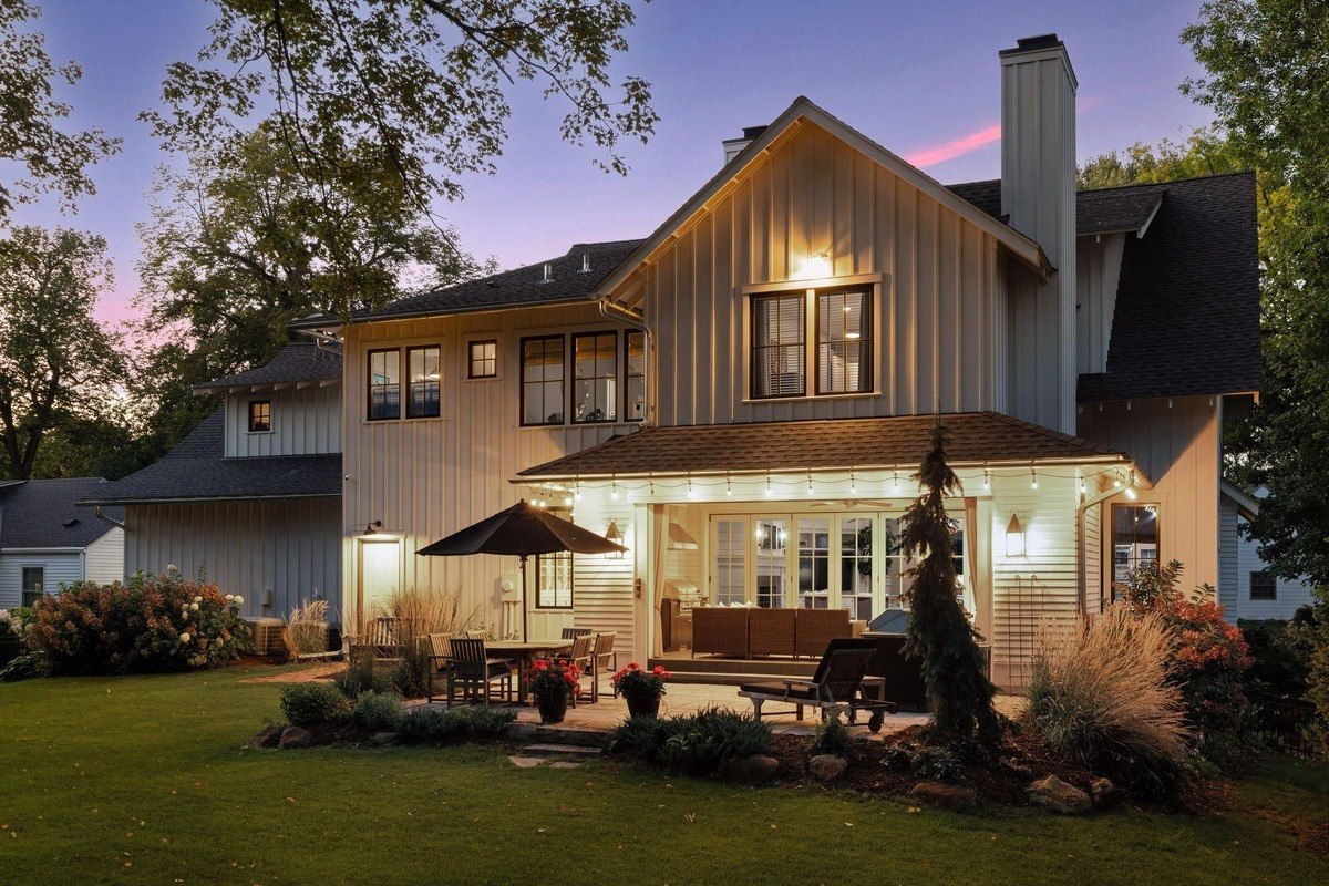 Back of a house with a patio, outdoor seating, and warm evening lighting.