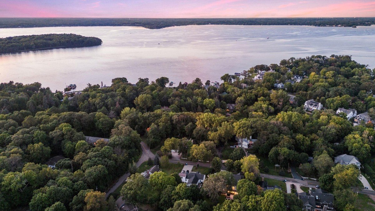 Aerial view of a neighborhood surrounded by trees with a nearby lake.