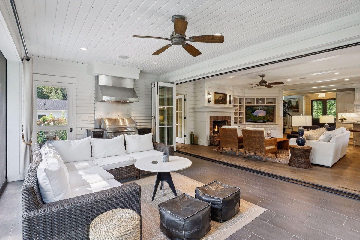 Outdoor living space a covered patio with a built-in grill, wicker furniture, and folding doors connecting it to the indoor living room.